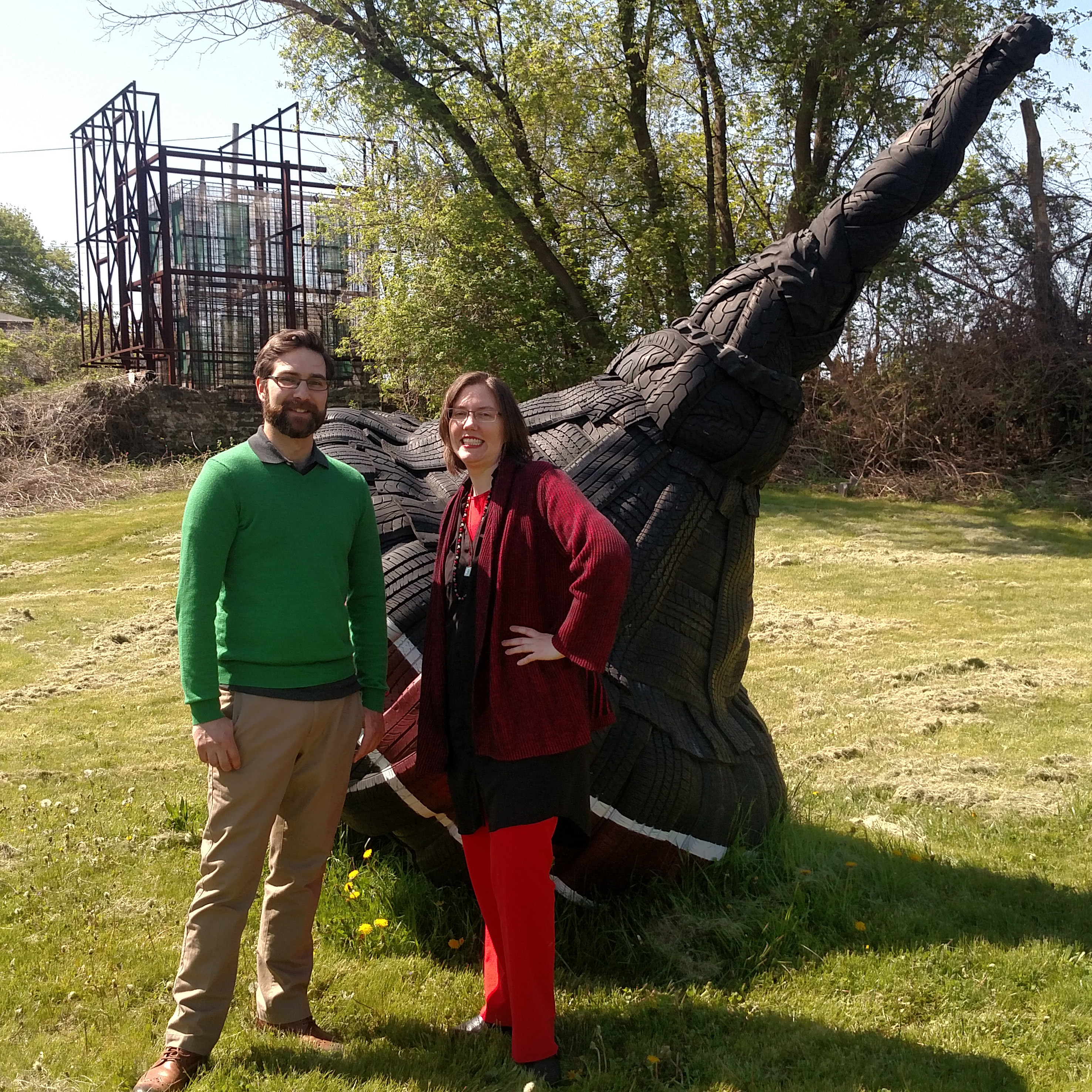 ArtOneida team members Marc-Anthony Polizzi and Arden Kirkland in the yard at Sculpture Space with Top by Anssi Taulu, with Translucent Home by Ann Reichlin in the background