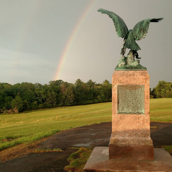 a back view of Utica's Eagle monument looking out at a rainbow in the background